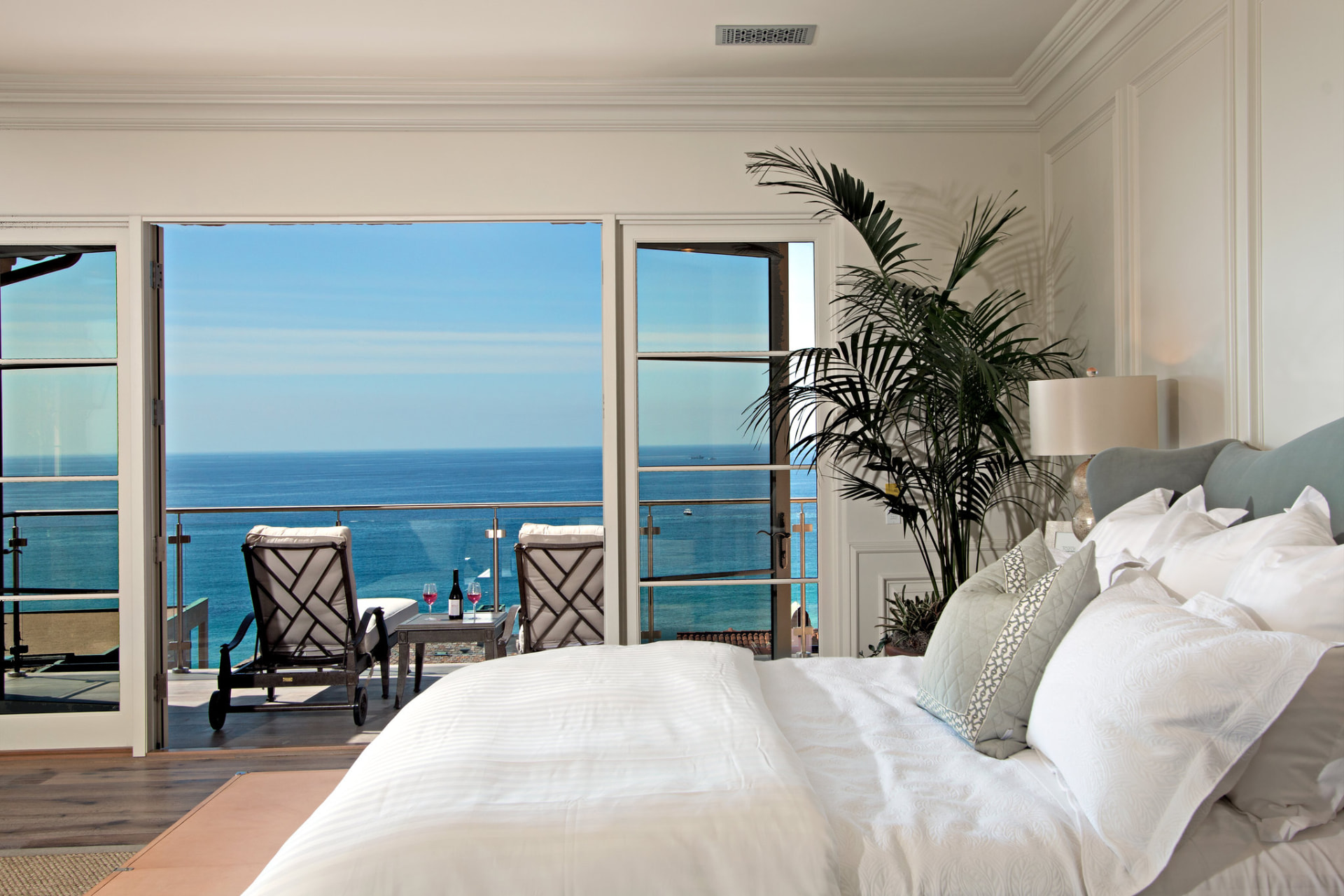 Staged luxury bedroom opening to a balcony with an ocean view, photographed by PreviewFirst